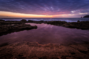 Wonderful sunset while cloudy sky reflects on sea water puddle