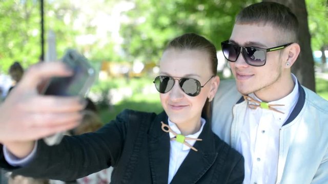 Beautiful young friends boy and girl browse photos on mobile phone in park