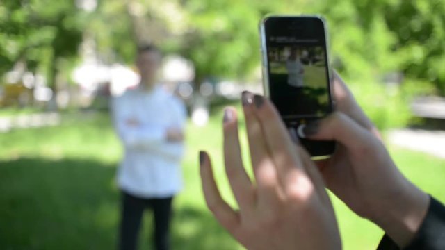 Beautiful young girl woman doing photos on mobile phone in park
