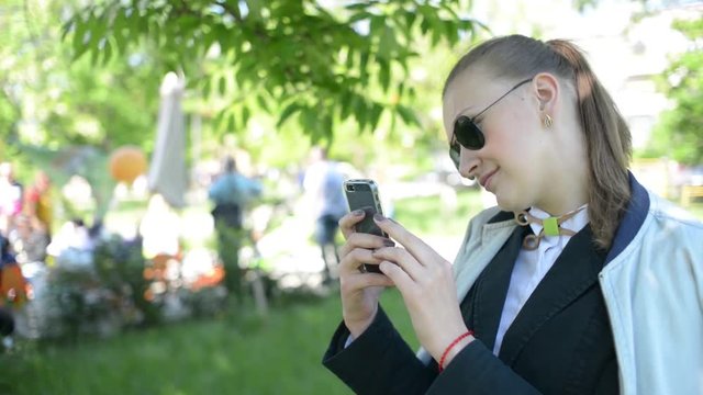 Beautiful young girl woman doing photos on mobile phone in park