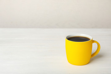 Yellow ceramic cup with hot aromatic coffee on table