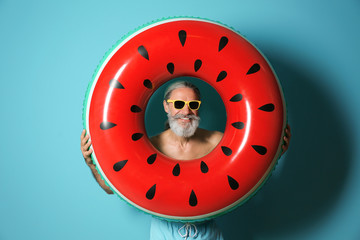 Naklejka premium Shirtless man with inflatable ring on color background