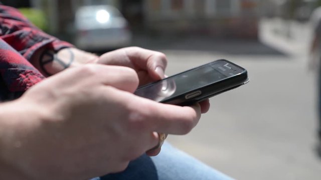 Mobile Cell Phone in the Hands of a Man - chating wrighting sms - in a city park