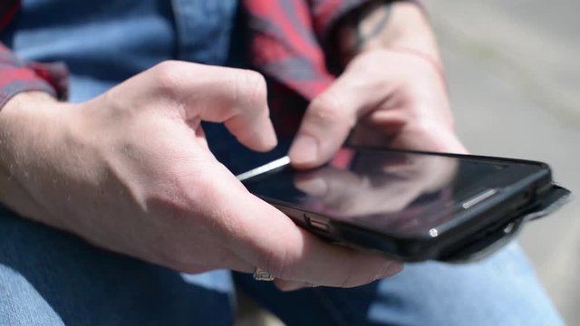 Mobile Cell Phone in the Hands of a Man - chating wrighting sms - in a city park