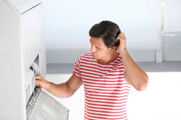 Fototapeta na wymiar Young man fixing air conditioner at home