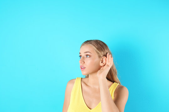 Young woman with hearing problem on color background