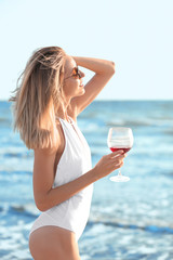 Young woman with glass of wine on beach
