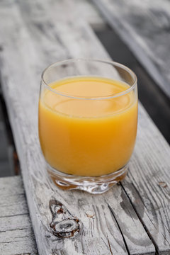 orange juice in the glass on wooden table