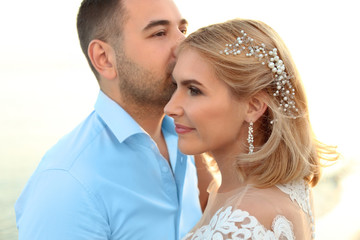 Wedding couple. Groom kissing bride on beach