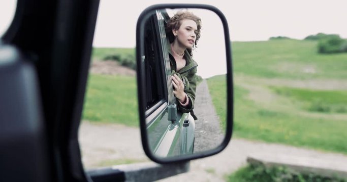 Reflection in mirror of young adult female on road trip