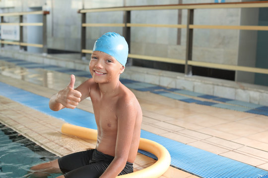 Little boy in swimming cap near indoor pool
