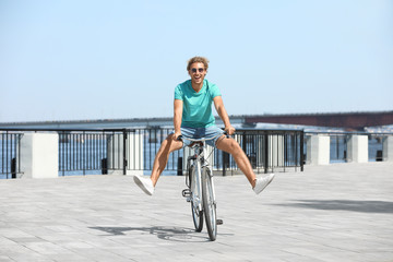 Handsome young man riding bicycle outdoors on sunny day