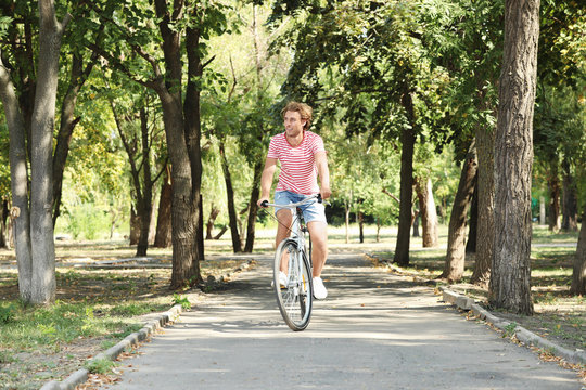 Handsome man riding bicycle in park on sunny day