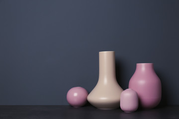 Beautiful ceramic vases on table against color wall with space for text