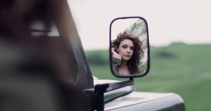 Reflection in mirror of young adult female on road trip