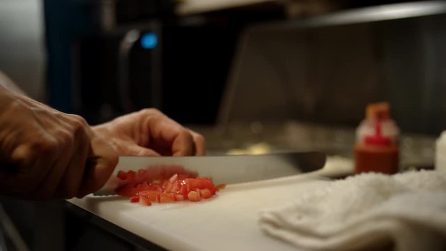 Close up of a chef chopping tomatoes in a restaurant kitchen