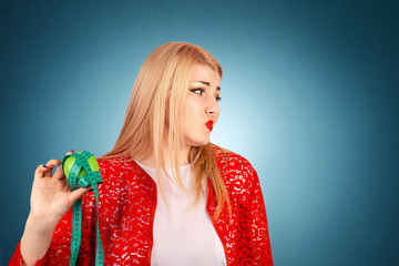 woman holding apple, measurement tape around apple turning face with disgust