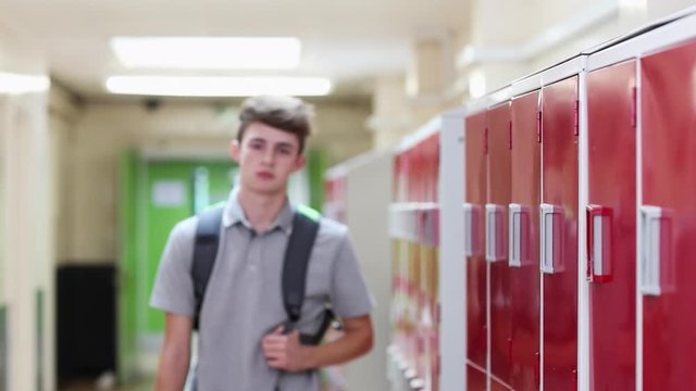 Portrait Of Male High School Student Walking Down Corridor And Smiling At Camera