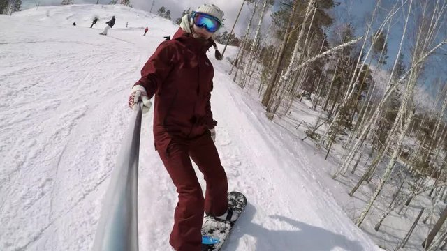 Snowboard Selfie. Female snowboarder takes selfie on GoPro camera while going down the hill