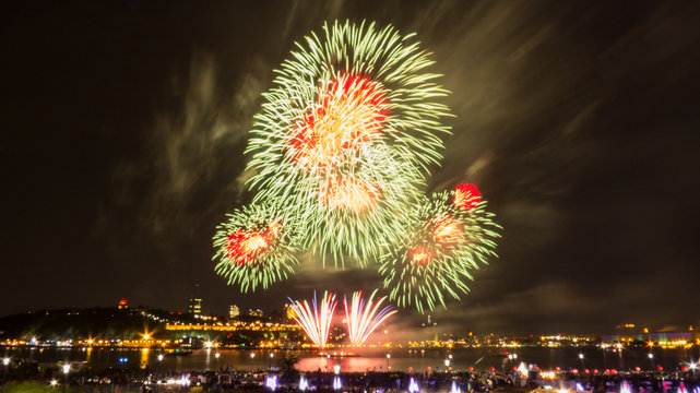 Red and green fireworks in front of Quebec City during a summer festival.