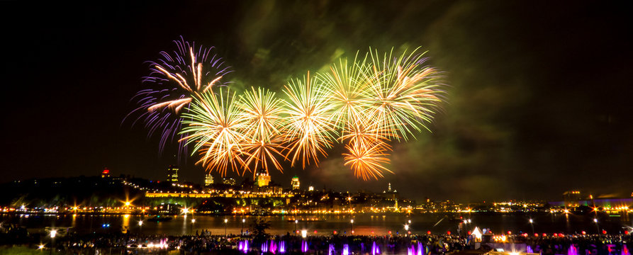 Orange and green fireworks in front of Quebec City during a summer festival.