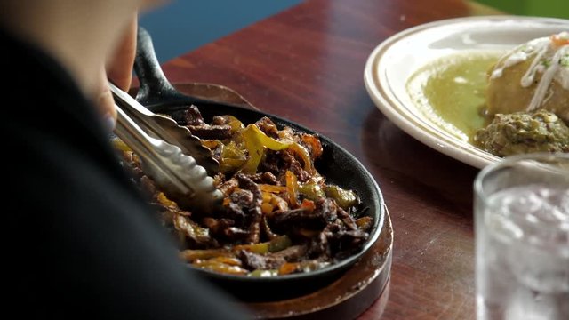 Close up shot of two delicious Mexican entrees, and two hands eagerly grabbing their silverware and digging in