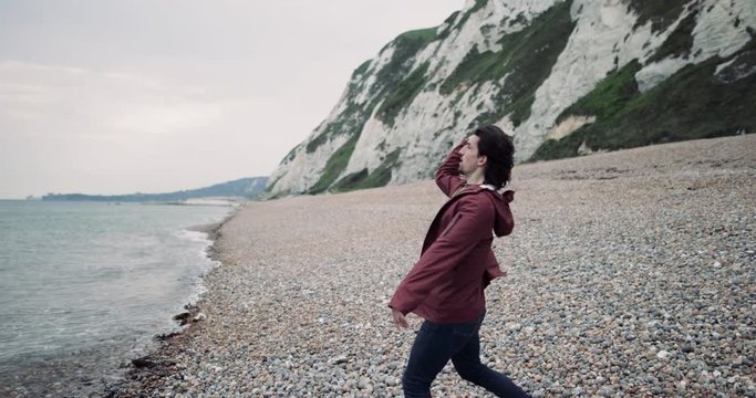 Millenial male throwing a stone into the sea