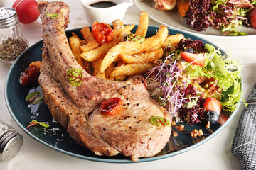 Barbecue tomahawk pork steak with salad  and french fries  on a plate