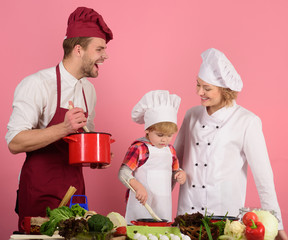Mom, dad and kid with busy face cooking food together. Happy family, childhood, food, cooking concept. Happy family preparing lunch in kitchen. Healthy lifestyle. Cooking at home. Preparing food, meal