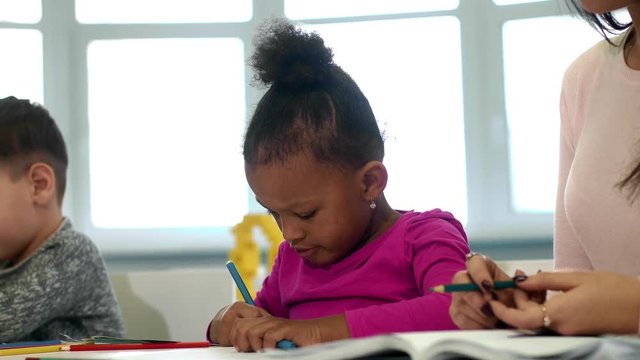 Young teacher working with her pre-school little students at classroom