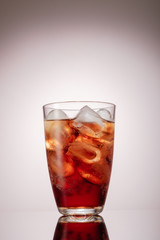 Cold glass of iced tea with ice cubes, grey background