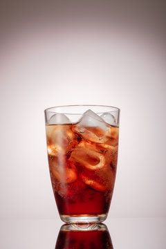 Cold glass of iced tea with ice cubes, grey background
