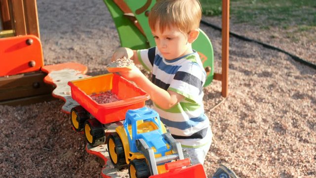 4k video of little concentrated toddler boy playing with trailer and loader in sandbox