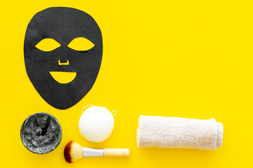 Black facial mask. Black head remover mask. Mask with clay on yellow background top view copy space