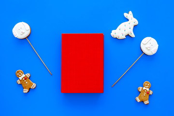 Developing entertainment for children. Book near sweets on blue background top view