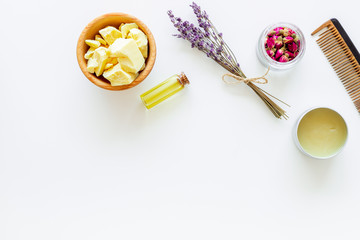 Hair treatment with natural products. Jojoba, argan, coconut oil near bunch of lavender and hairbrush on white background top view copy space