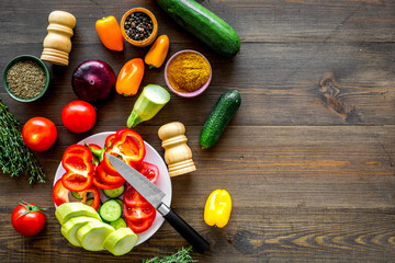 Healthy food concept. Ingredients for vegetable stew. Squash, bell pepper, tomato, spices, oil on dark wooden background top view copy space