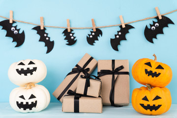 Yellow ghost pumpkin with gift box and bat on sky blue background. halloween concept.