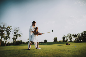 Father Playing Golf with Little Daughter on Field.