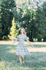 Naklejka premium beautiful girl in the Park, in a summer dress and walking. Smiles and enjoys nature. St. Petersburg, Yelagin island