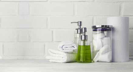 Part of spa interior. Cotton napkins, cotton pads, tissue, towels, soap and cosmetic products on a wooden table. White  background and table. Copy space. Selective focus.