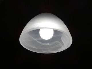 Nightlight in the darkness of the night with a burning white light bulb