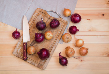 Onions on cutting board and near on wooden background. Top view.