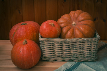 Different pumpkins in wicker basket and near