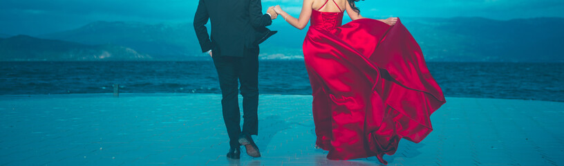 unrecognizable groom and bride in red satin dress