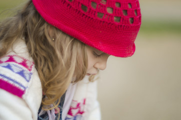 Shallow depth of field close up shot of a cute girl with curly blonde hair. She looks sad and lonely. Looking down.