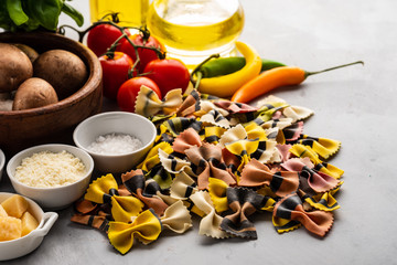Not cooked farfalle pasta, with a set of products and ingredients for cooking traditional Italian food