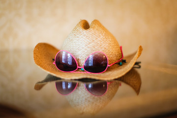 summer cowboy Woven hat and sunglasses with reflection on glass table
