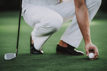 Obraz premium Young Man in White Clothes Playing Golf on Field.