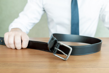 Office Man in white shirt and tie is holding a belt, punishment concept